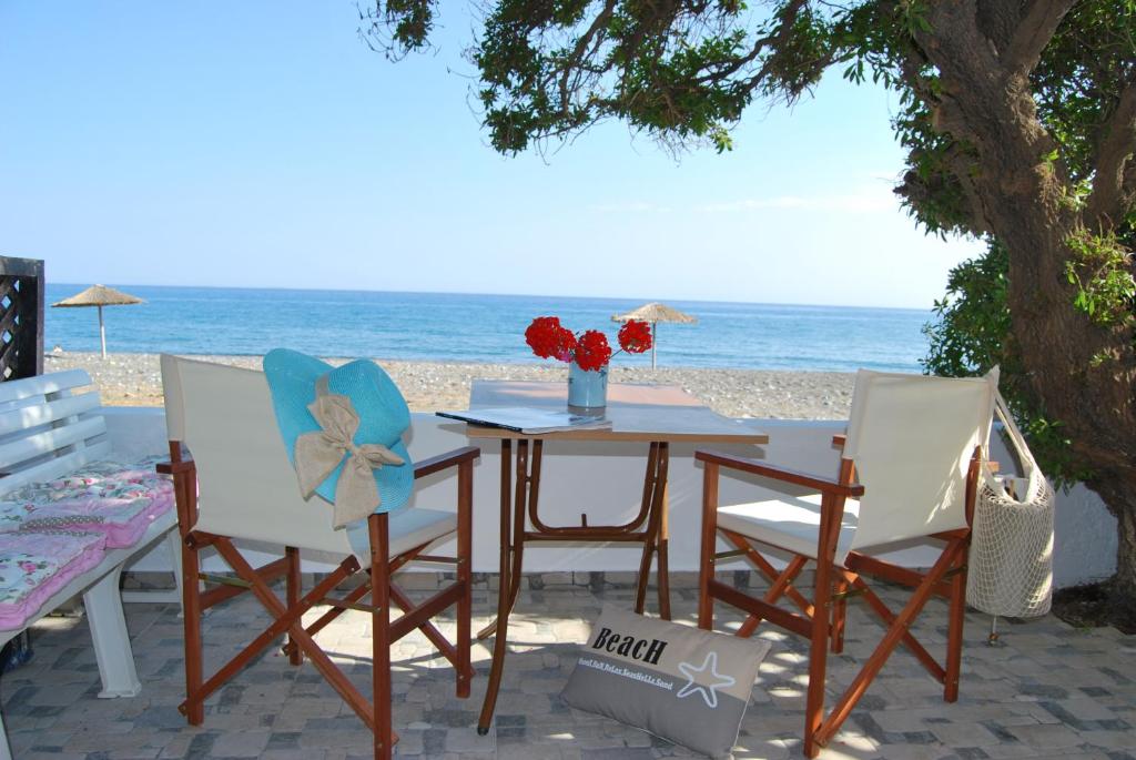 een tafel en stoelen op het strand met de oceaan bij Hatzidakis Beach Retreat in Ierápetra
