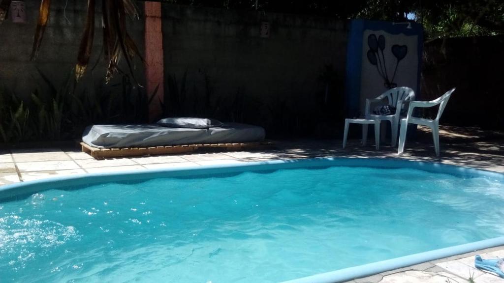 uma grande piscina com uma cama e uma cadeira em Casa das Gaúchas em Canoa Quebrada