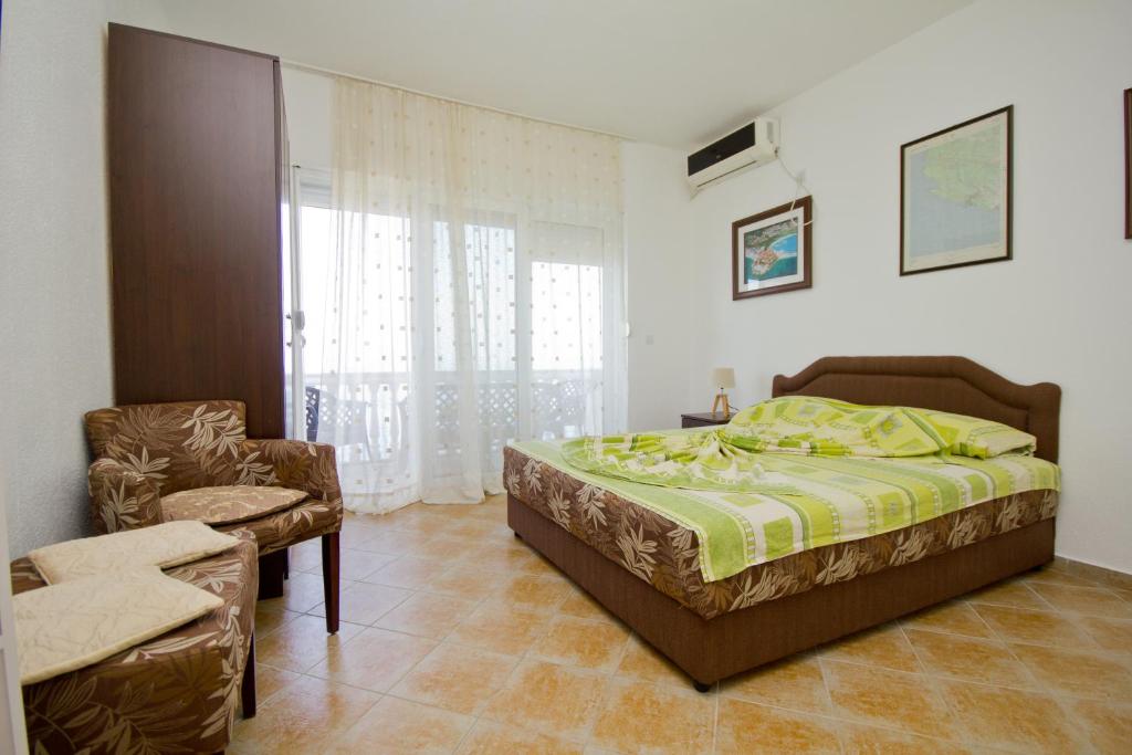 a bedroom with a bed and a chair and a window at Apartments Dora in Dobra Voda