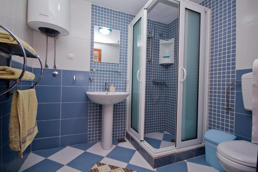 a blue tiled bathroom with a shower and a sink at Apartments Dora in Dobra Voda