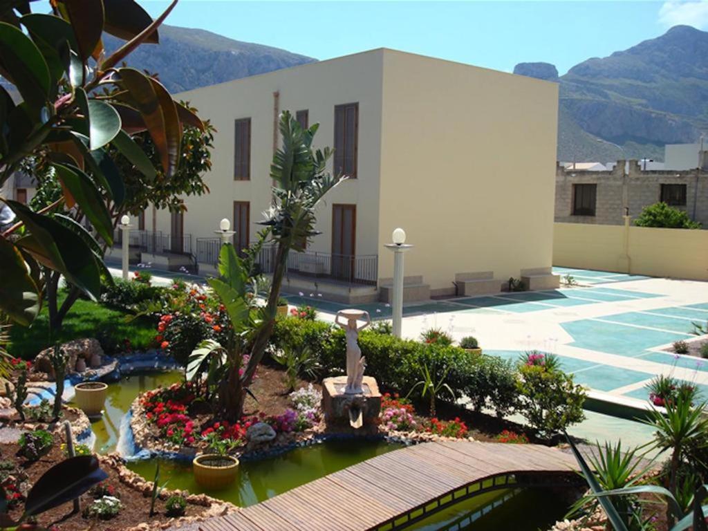 a courtyard with a garden with flowers and a building at Coral sea in San Vito lo Capo