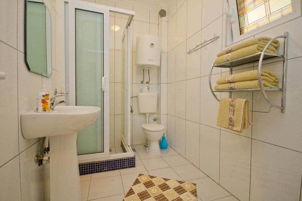a white bathroom with a sink and a toilet at Apartments Dora in Dobra Voda