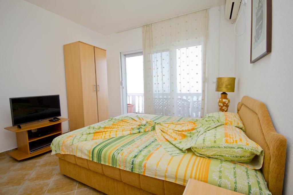 a bedroom with a bed and a tv and a window at Apartments Dora in Dobra Voda