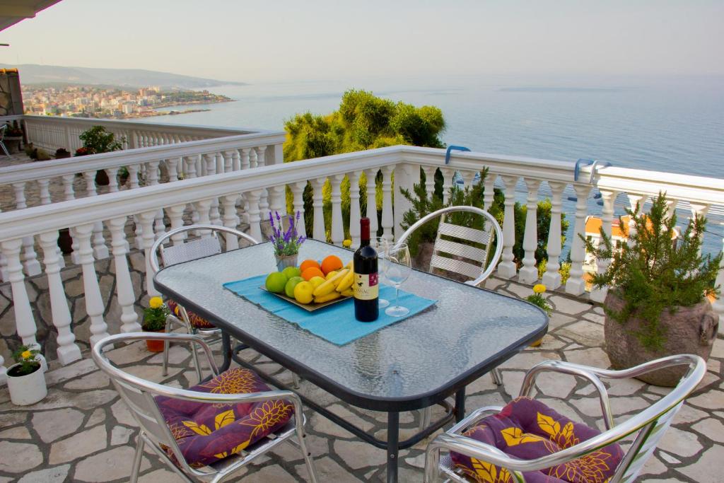 a table with a bottle of wine and fruit on a balcony at Apartments Dora in Dobra Voda