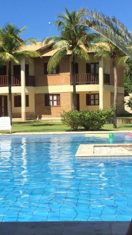 uma piscina em frente a um edifício com palmeiras em Club house em Prainha