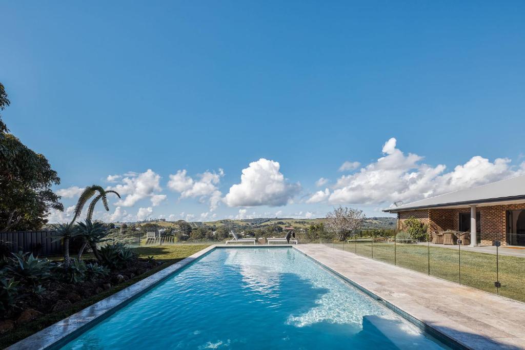 
a large swimming pool in front of a house at 99 Acres Bangalow Retreat in Bangalow
