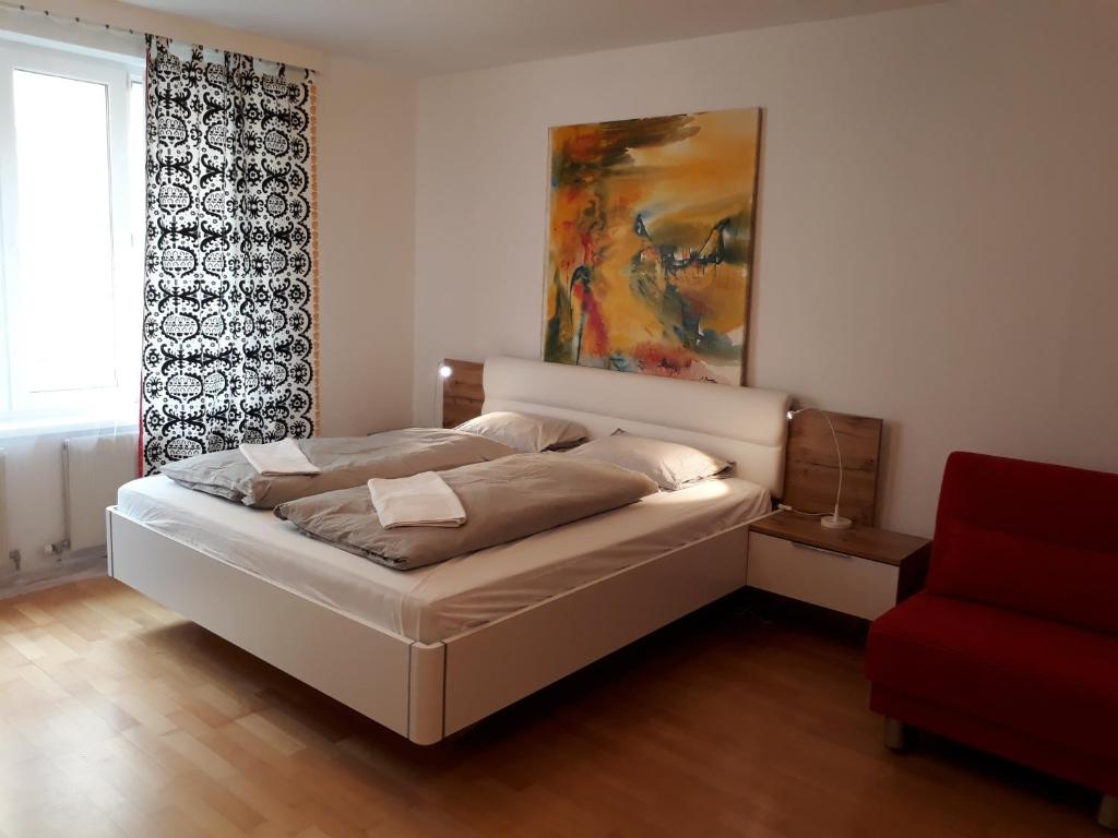 ein Schlafzimmer mit einem Bett, einem Fenster und einem roten Stuhl in der Unterkunft cute Metro U4 in Wien