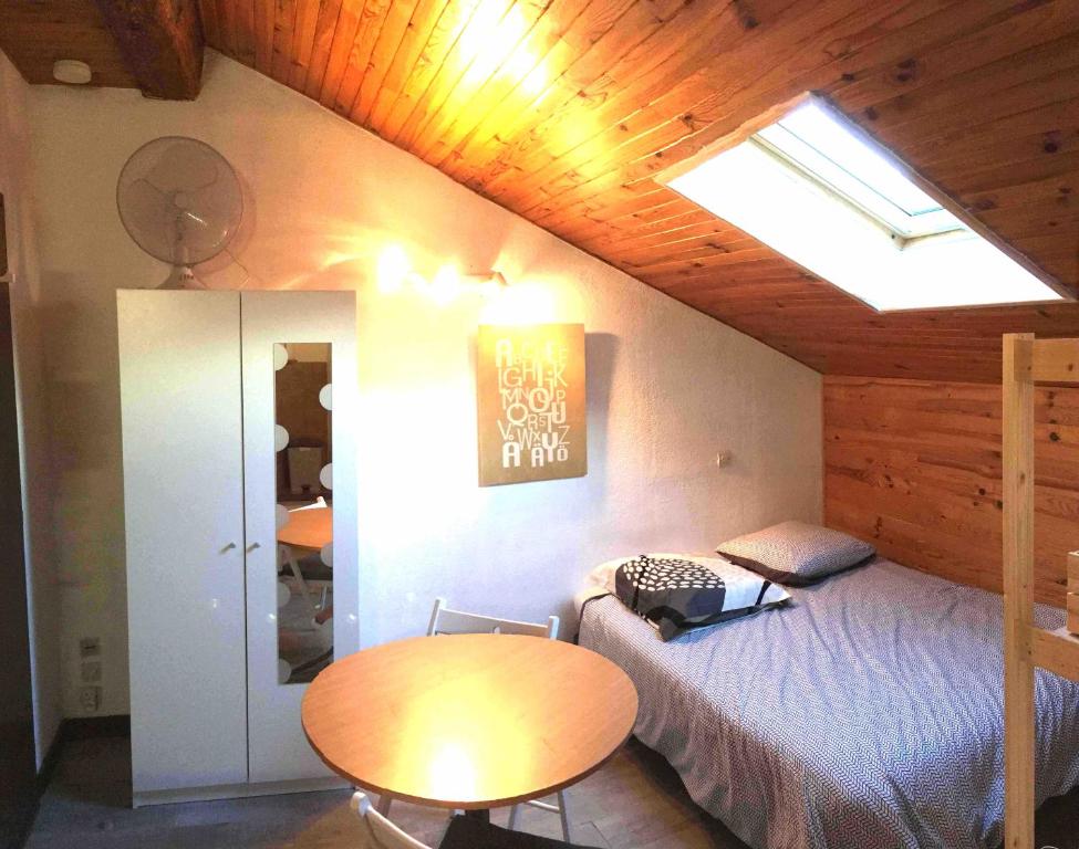 a bedroom with a bed and a table and a skylight at Studio Alphabet in Chambéry