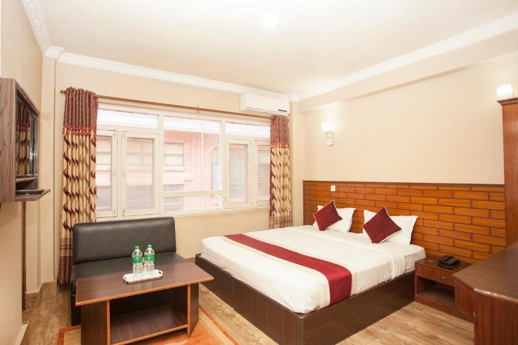 a hotel room with a bed and a window at Hotel Holiday Taj (p) Ltd in Kathmandu