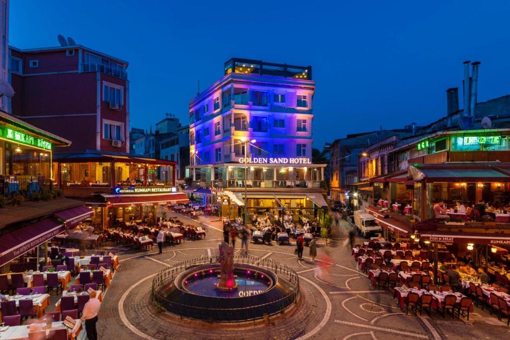 eine Stadtstraße mit Leuten, die vor Gebäuden an Tischen sitzen in der Unterkunft Golden Sand Hotel in Istanbul