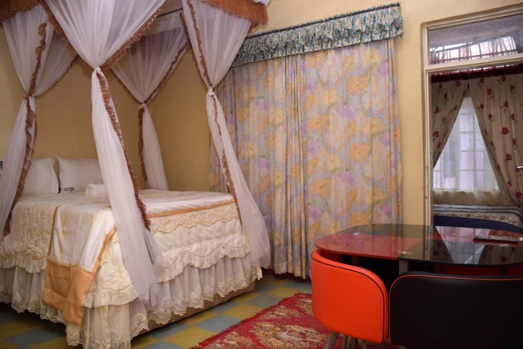 1 dormitorio con cama con dosel y mesa de cristal en Right Venue Hotel en Thika