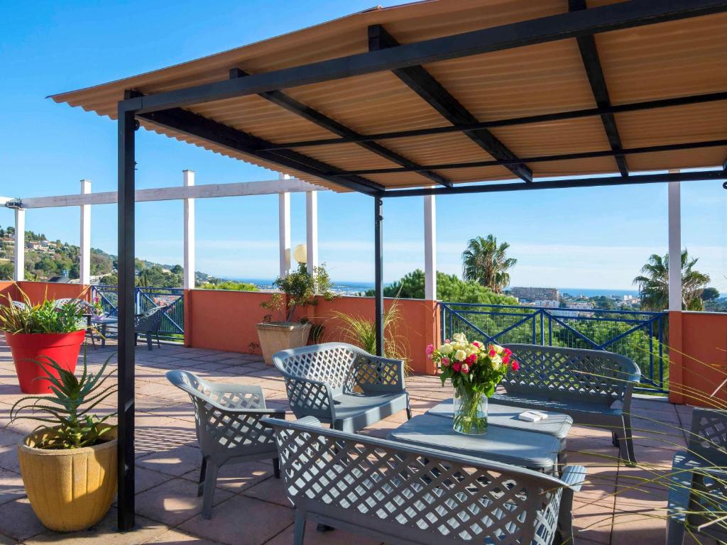 un patio avec des chaises et une table avec des fleurs dessus dans l'établissement ibis budget Cannes Mougins, à Mougins