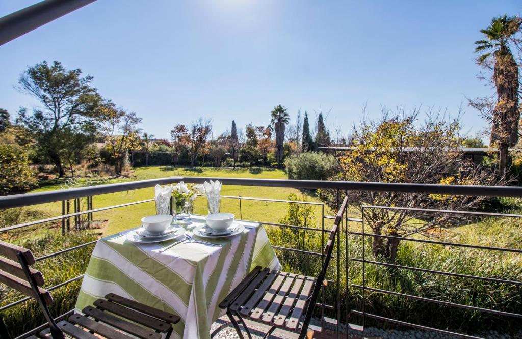 a table on a balcony with a view of a field at Craigivar Guesthouse in Pretoria