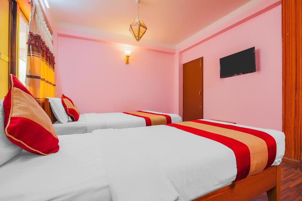two beds in a room with pink and red at Hotel Everest Window View in Nagarkot
