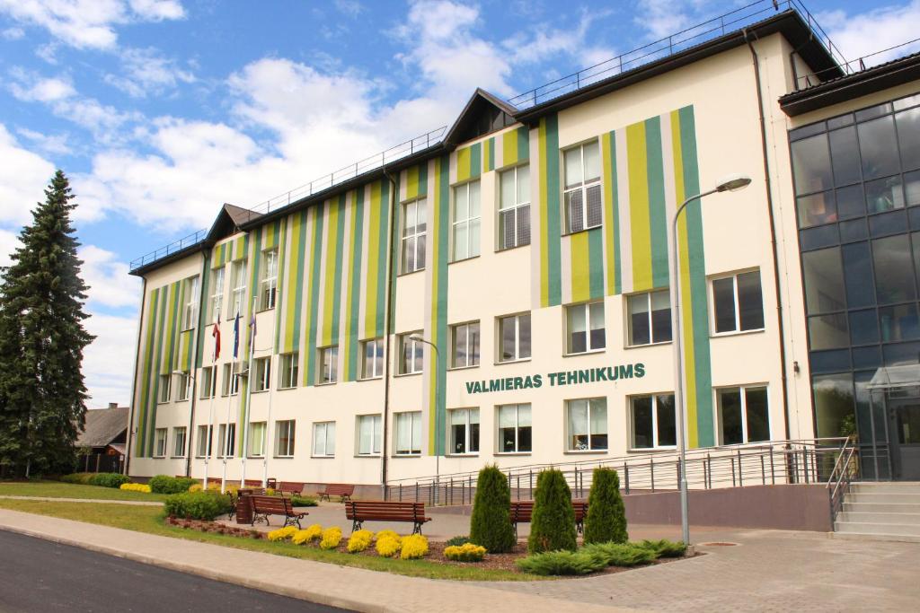 ein großes weißes Gebäude mit grünen und gelben Streifen in der Unterkunft Valmieras tehnikuma dienesta viesnīca in Valmiera