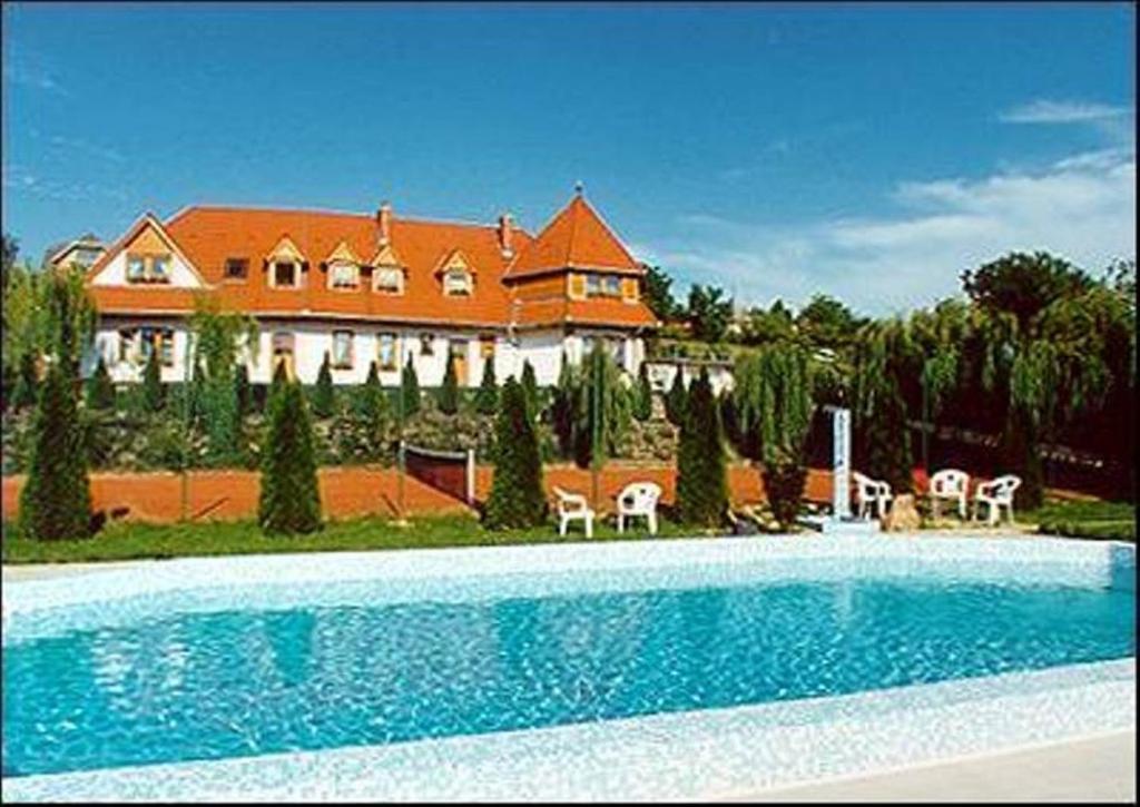 une grande maison avec une piscine en face d'une maison dans l'établissement Palatinus Apartmanok, à Keszthely