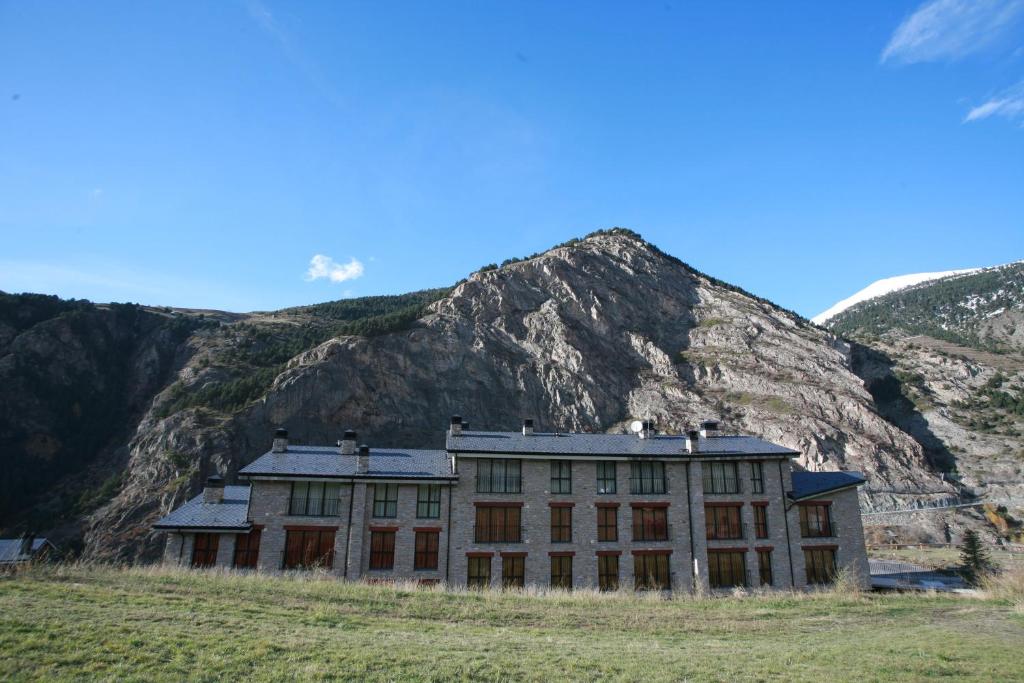 um edifício antigo em frente a uma montanha em Obaga Blanca & Spa em Canillo