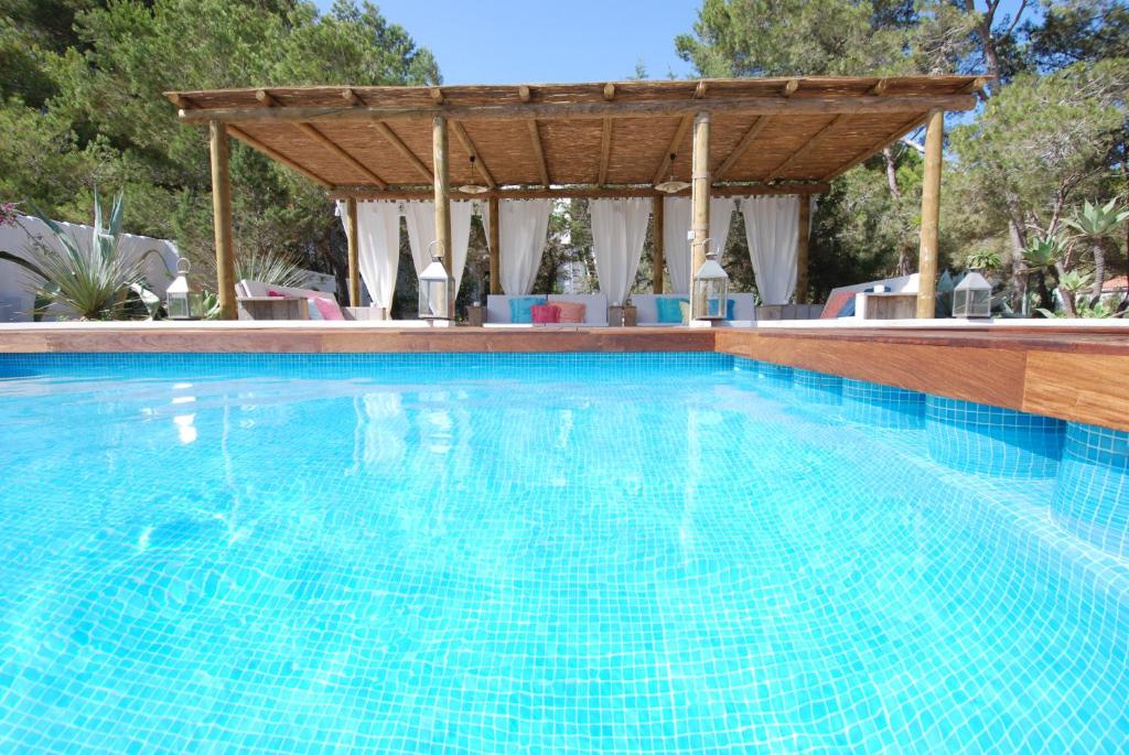 a swimming pool with a wooden pergola and a swimming pool at La Hacienda in San Ferrán de ses Roques