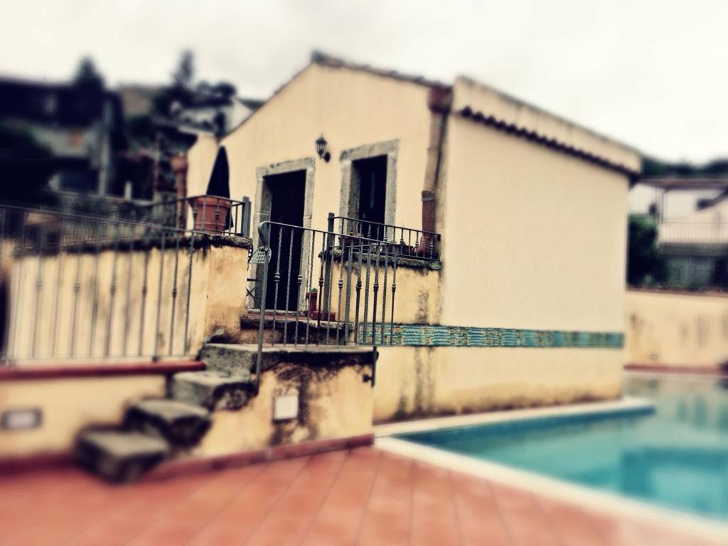 a building with a swimming pool in front of a house at The Clock Houses Borgo Gallodoro in Letojanni