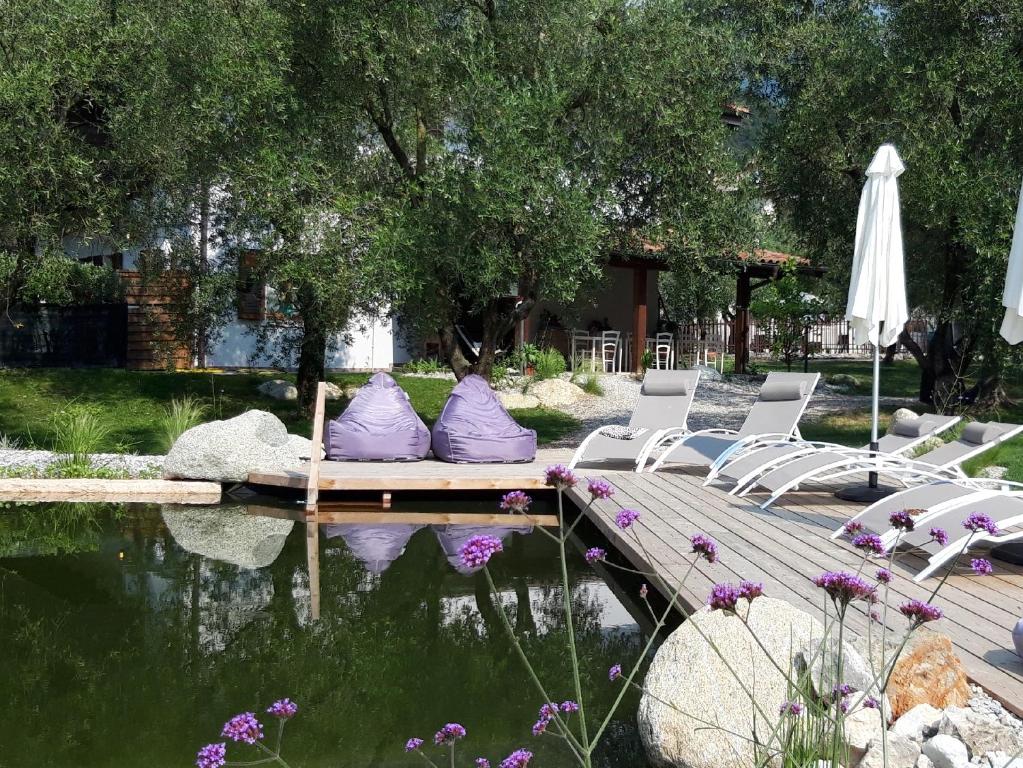 eine Gruppe Stühle und ein Regenschirm neben einem Teich in der Unterkunft Agritur Fiore d'Ulivo in Riva del Garda