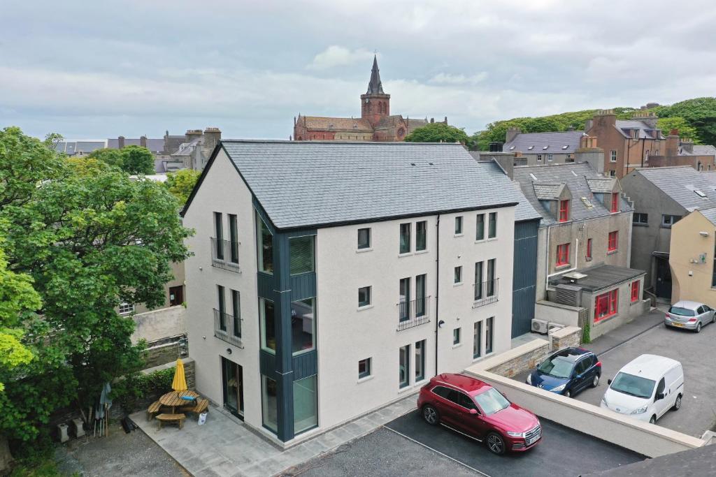 an apartment building with a red car parked in a parking lot at Apt 2, Frasers Close in Kirkwall