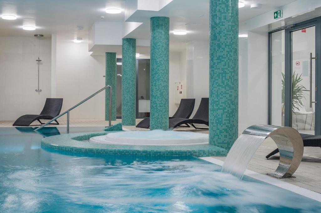 a pool with blue water in a room with chairs at Henryk in Świnoujście