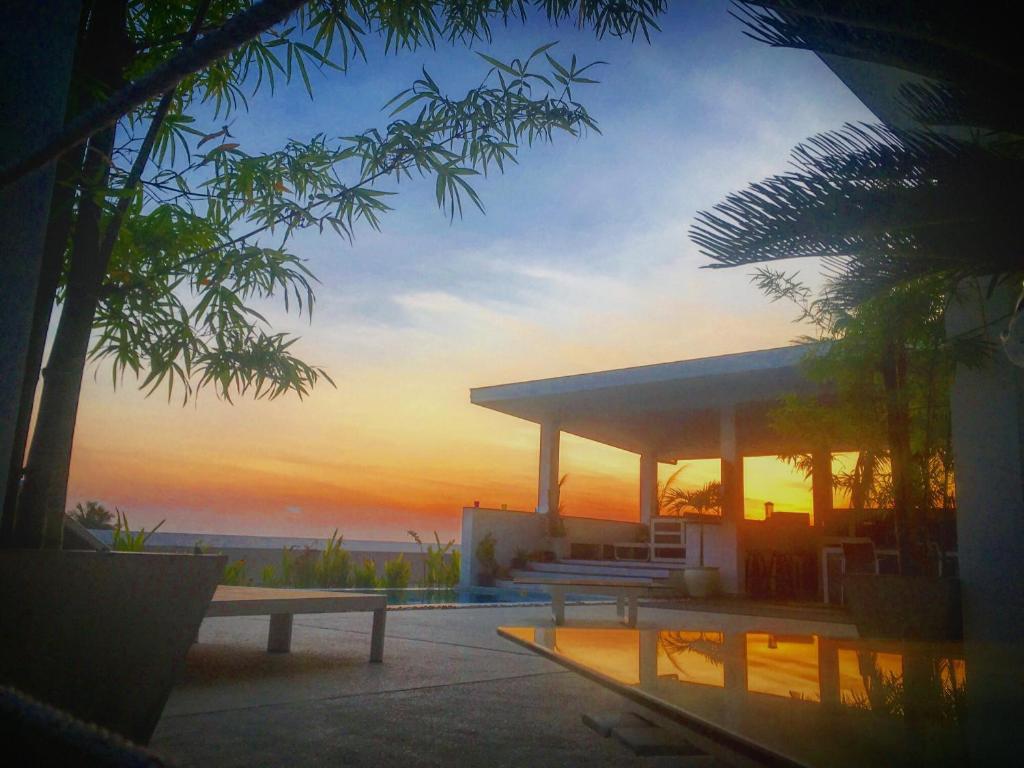 a building with a bench and a sunset in the background at La Villa Noi in Ban Ko Khwan