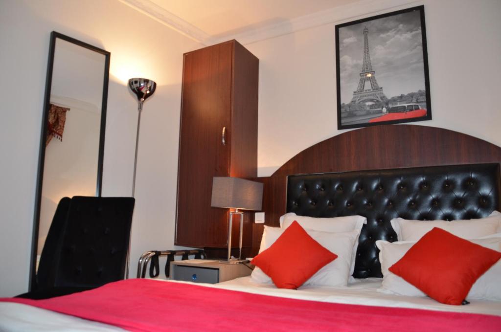 una camera da letto con letto con cuscini rossi e la torre Eiffel di Hotel Regina Montmartre a Parigi