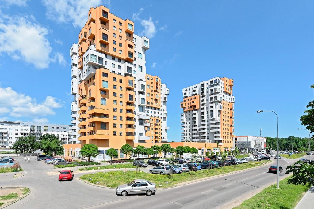 ulica z samochodami zaparkowanymi przed wysokimi budynkami w obiekcie Comfort Apartments Horyzonty w Gdańsku