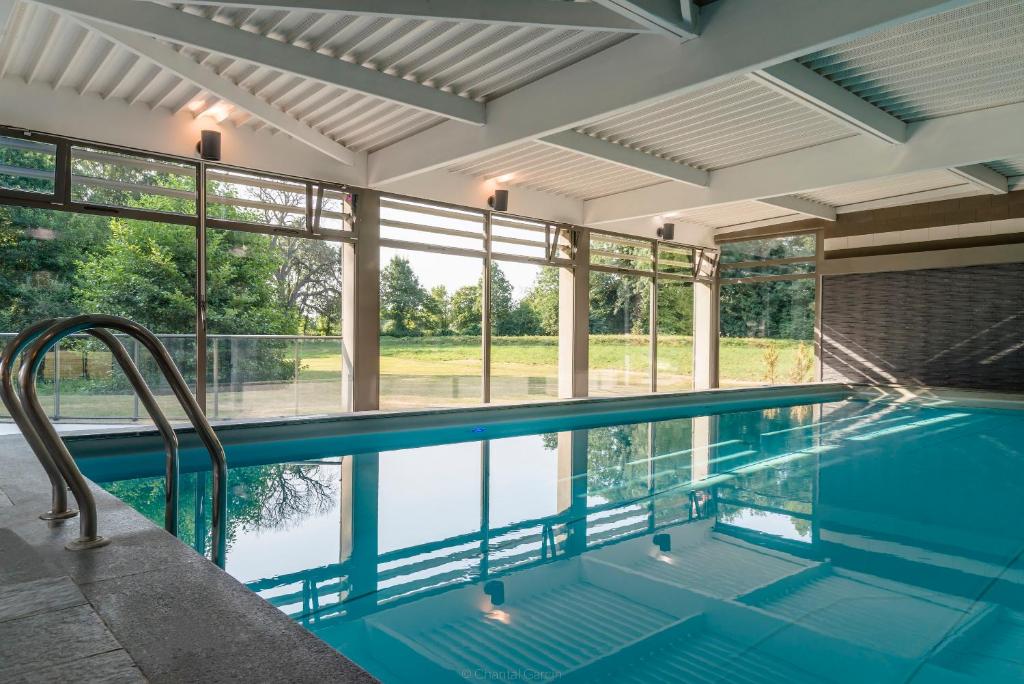 an indoor swimming pool with a view of the water at Hôtel Château Tilques in Tilques