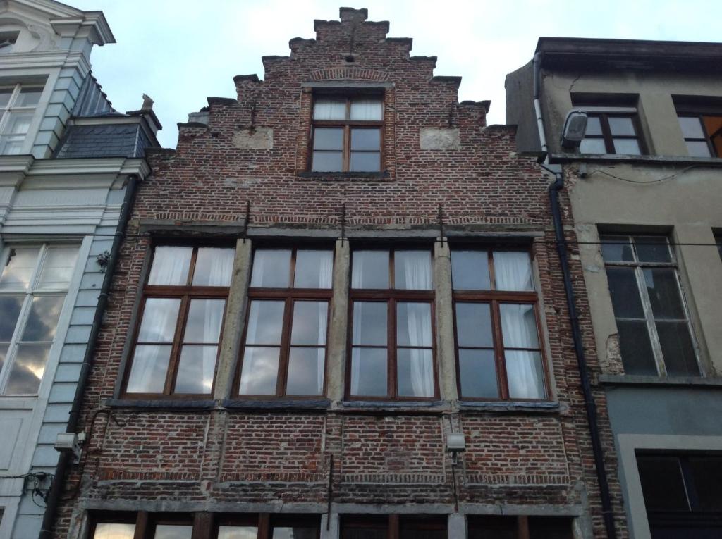 a brick building with windows on a city street at Geldmunt Apartment in Ghent