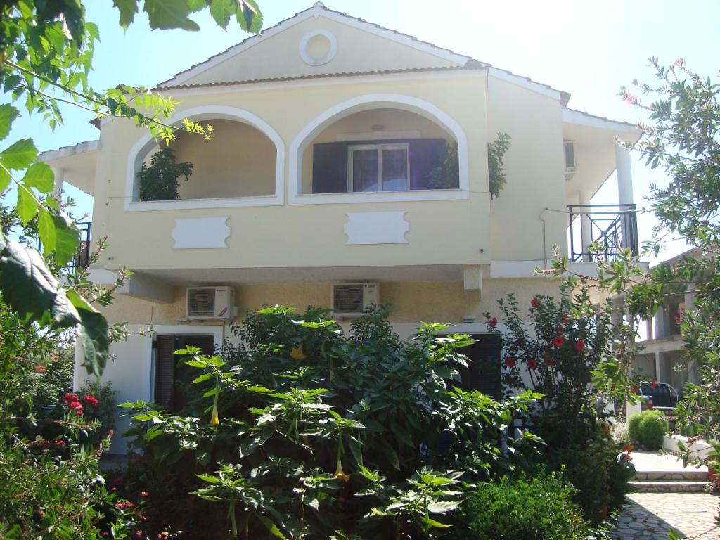 a large white house with plants in front of it at Olga Apartments in Agios Georgios