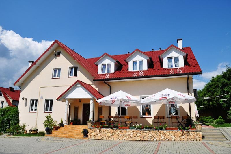 a large white house with umbrellas in front of it at Pensjonat U Bogusi in Berezka