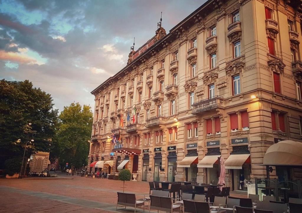 een groot gebouw met stoelen ervoor bij Grand Hotel Regina Salsomaggiore in Salsomaggiore Terme