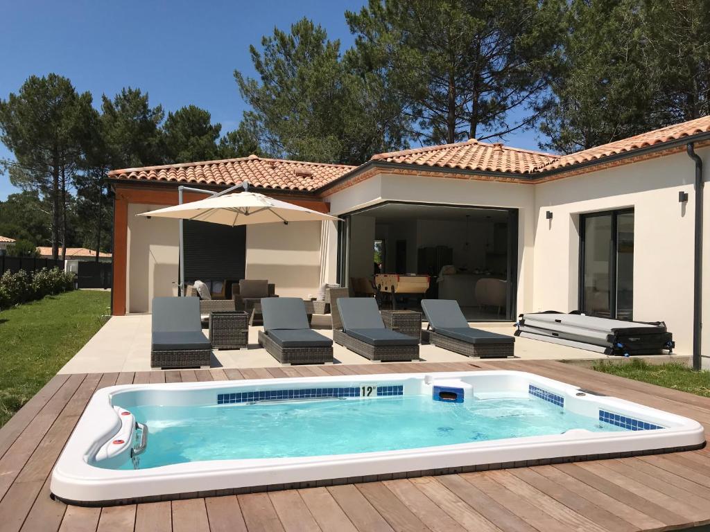 a swimming pool in front of a house at Location villa entre lac et océan avec son spa de nage in Carcans