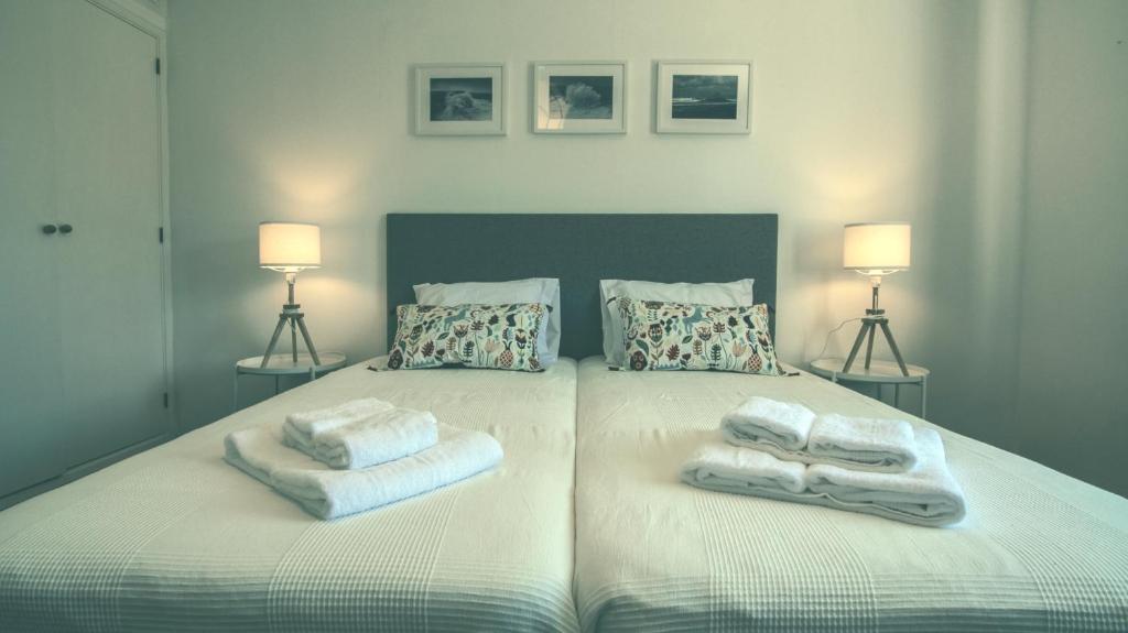 a bedroom with two towels on a bed with two lamps at Pine House - Faro Airport, Beach and City Center in Faro