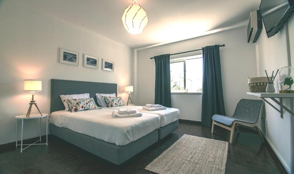 a bedroom with a bed and a chair and a window at Pine House - Faro Airport, Beach and City Center in Faro