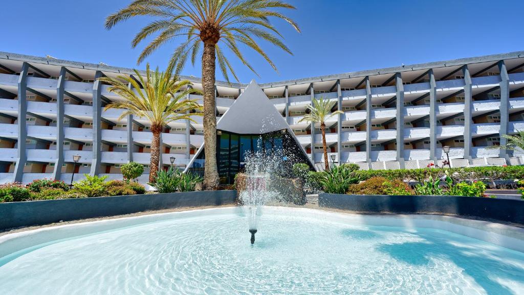 una fuente frente a un edificio con palmeras en Ura Jardín Del Atlántico en Playa del Inglés