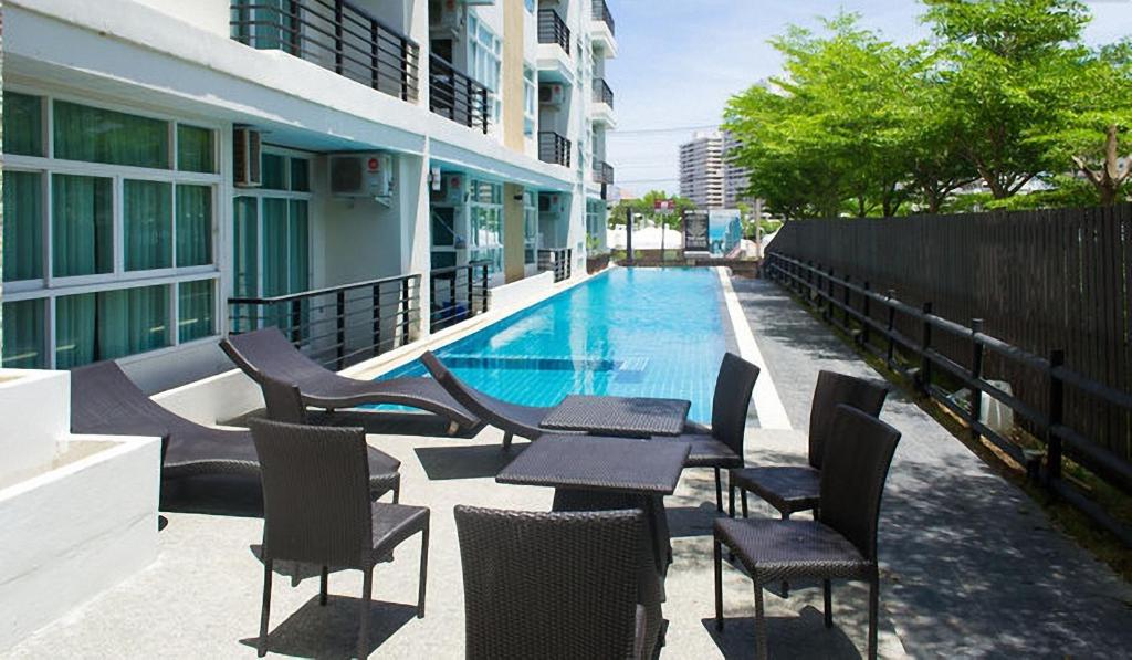 a swimming pool with tables and chairs next to a building at The Ocean Pearl in Pattaya South