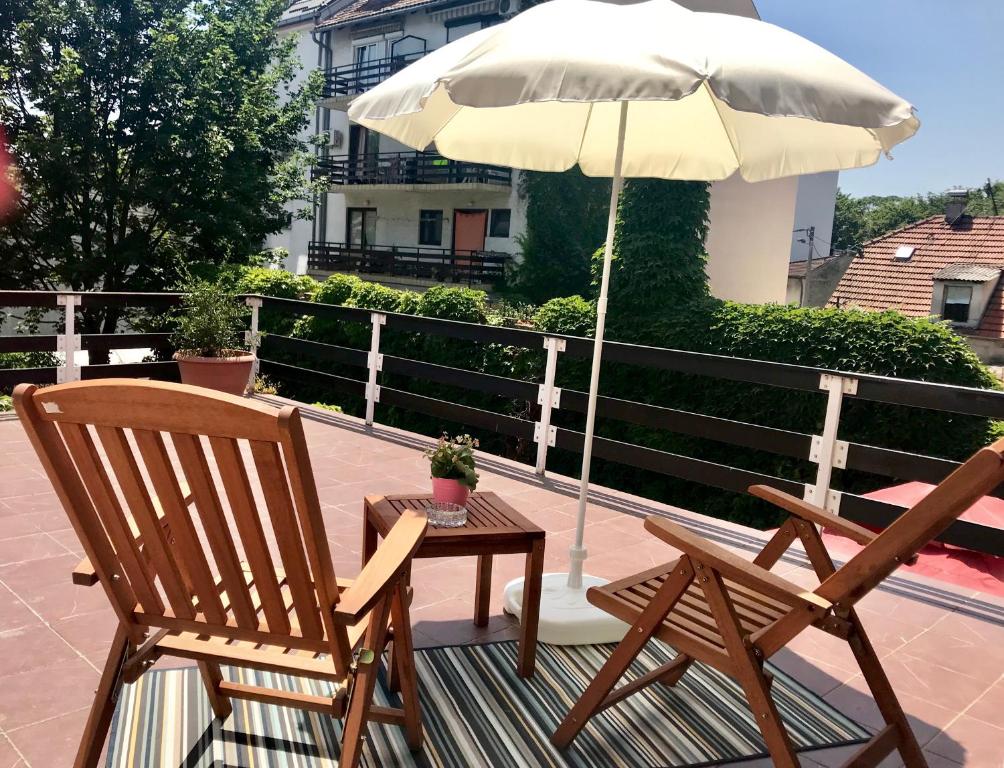 two chairs and a table with an umbrella on a balcony at MonikaRooms in Zagreb