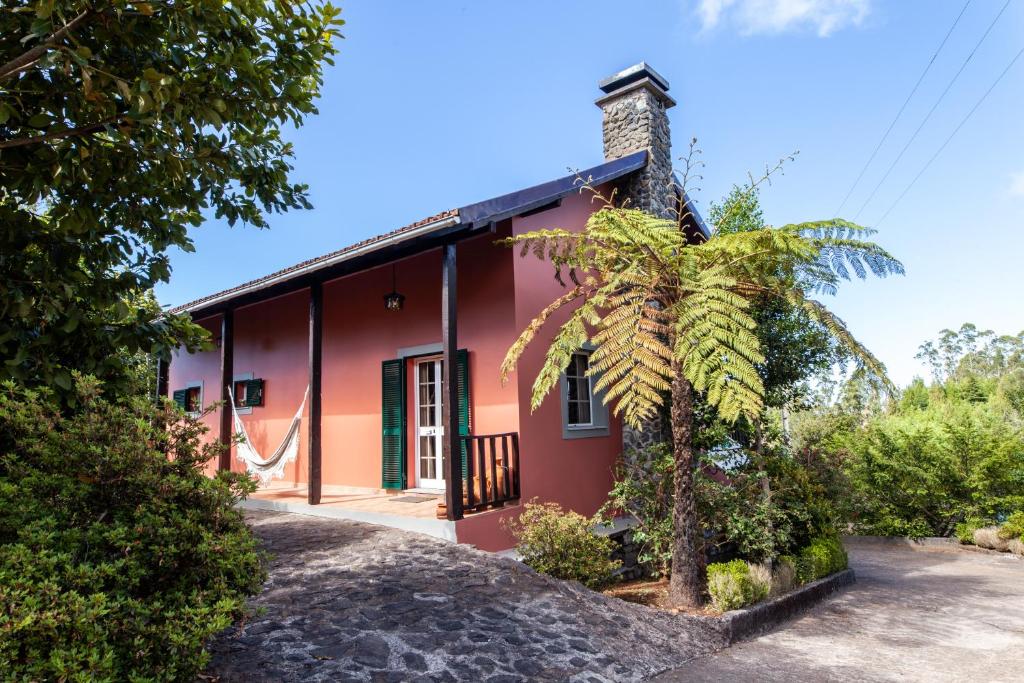 une maison rouge avec un palmier devant elle dans l'établissement Chalet Pico das Pedras, à Santana