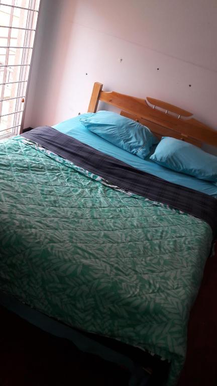 a bedroom with a bed with a green comforter at Habitaciones Altos de Cooservicios in Tunja