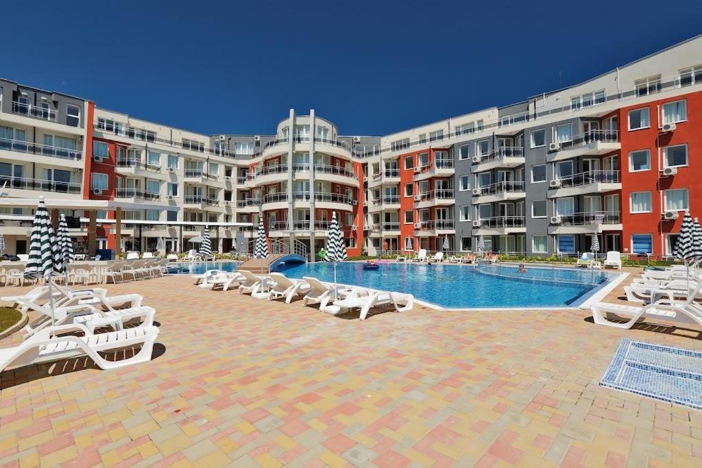 - une piscine avec des chaises longues blanches et des bâtiments dans l'établissement Private apartment in Emberli Aparthotel, à Lozenets