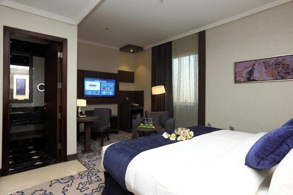 a hotel room with a bed and a living room at Swiss Flora Royal Hotel Riyadh in Riyadh