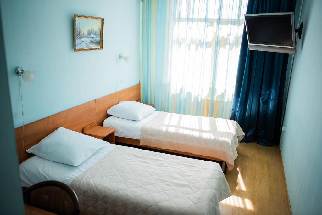 Cette petite chambre comprend 2 lits et une fenêtre. dans l'établissement Oktyabrskaya Hotel, à Tver