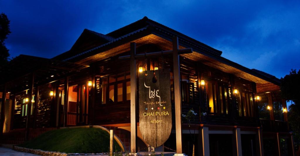 un bâtiment avec un panneau devant lui la nuit dans l'établissement Chaipura Resort, à Ko Chang