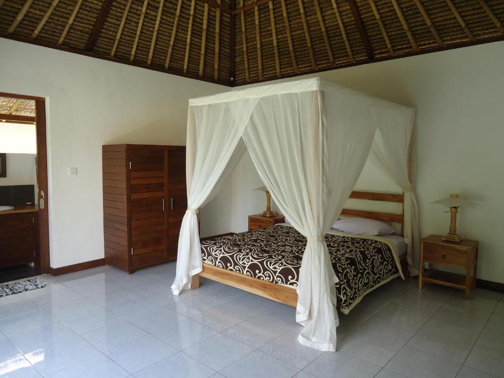a bedroom with a bed with a canopy at Suka's House Bed & Breakfast in Ubud