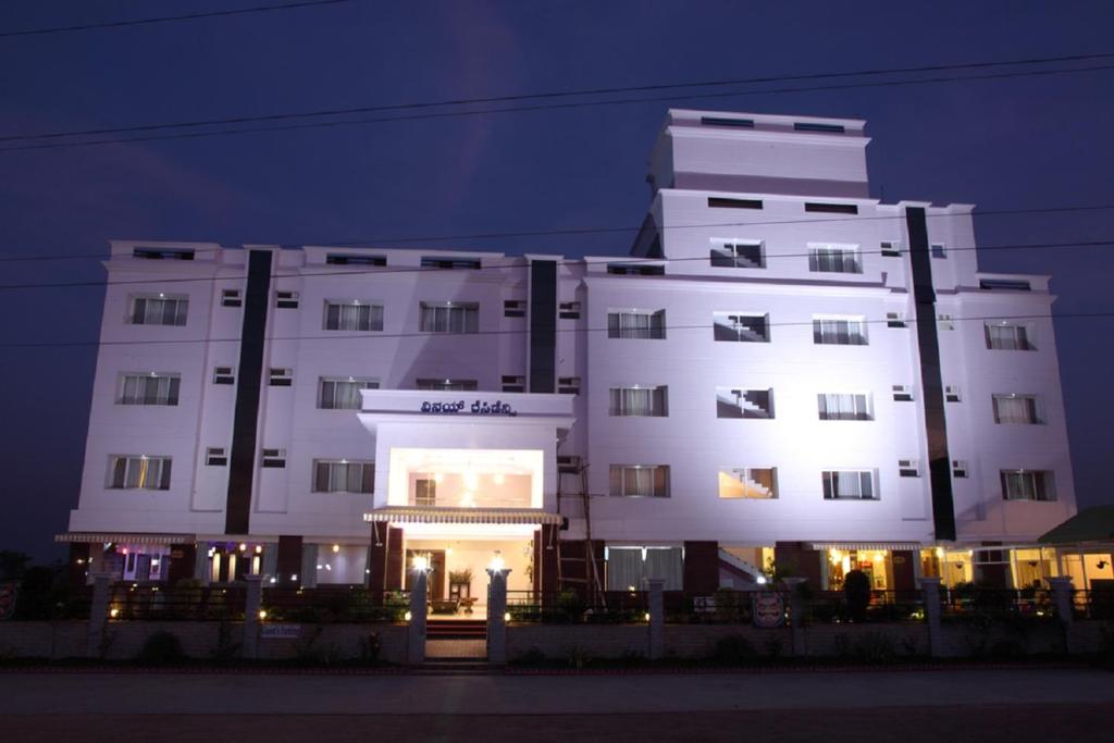 a large white building at night with its lights on at Vinay Residency in Sindhnūr