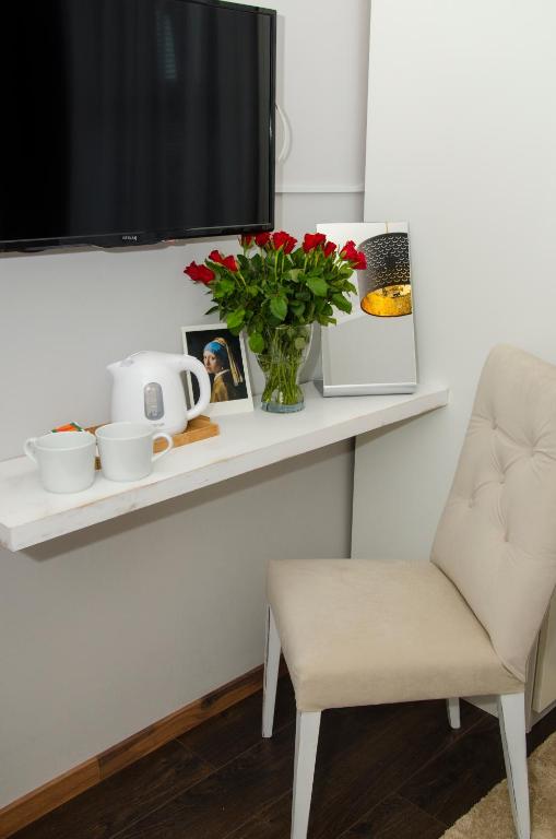 ein weißes Regal mit einer Vase aus Blumen und einem Stuhl in der Unterkunft Serendipity in Smederevo