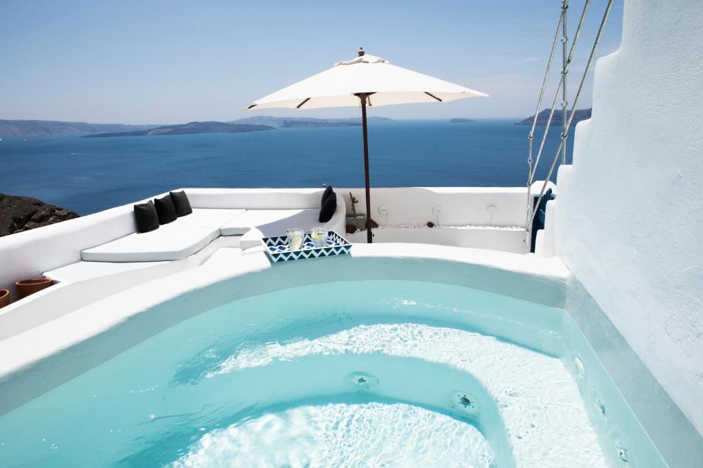 a hot tub with an umbrella next to the water at Oia's Secret in Oia